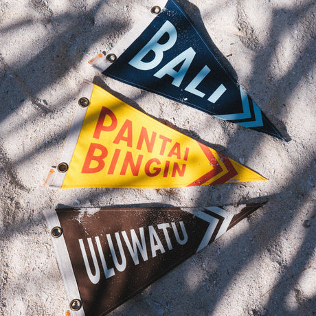 Three triangular flags with 'Bali', 'Pantai Bingin ', and 'Uluwatu' from Club Pantai