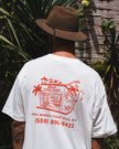 A person wearing a white Club Pantai t-shirt with Laundry Shop printed on it.