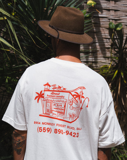 A person wearing a white Club Pantai t-shirt with Laundry Shop printed on it.