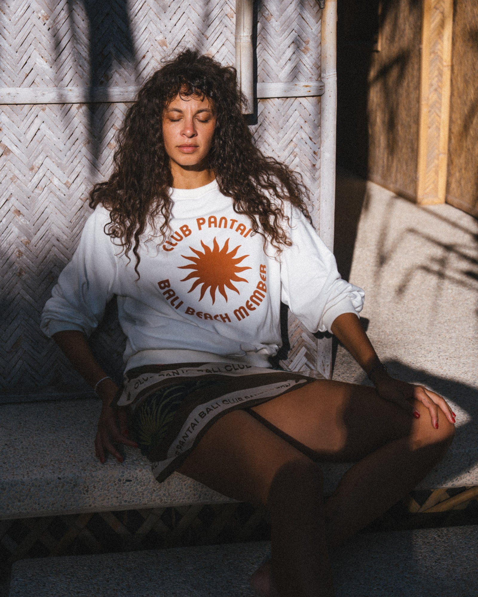 A woman wearing a Club Pantai white t-shirt.