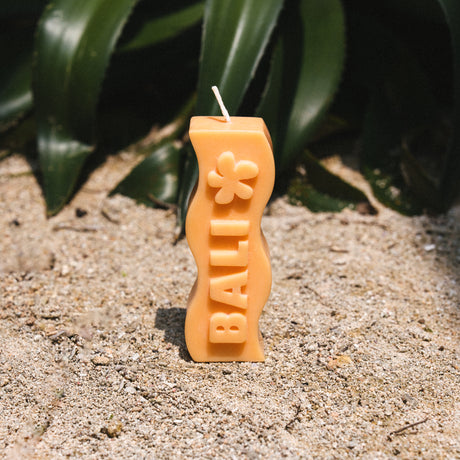 Club Pantai orange candle shaped like a dog bone with 'Bali' branding on sand