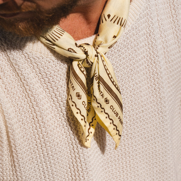 Club Pantai yellow bandana with black patterns tied.